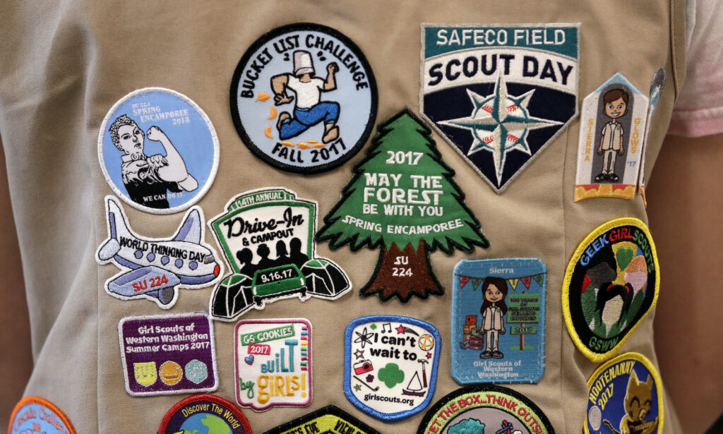 Girl Scouts vs Boy Scouts Patches cover the back of a Girl Scout's vest
