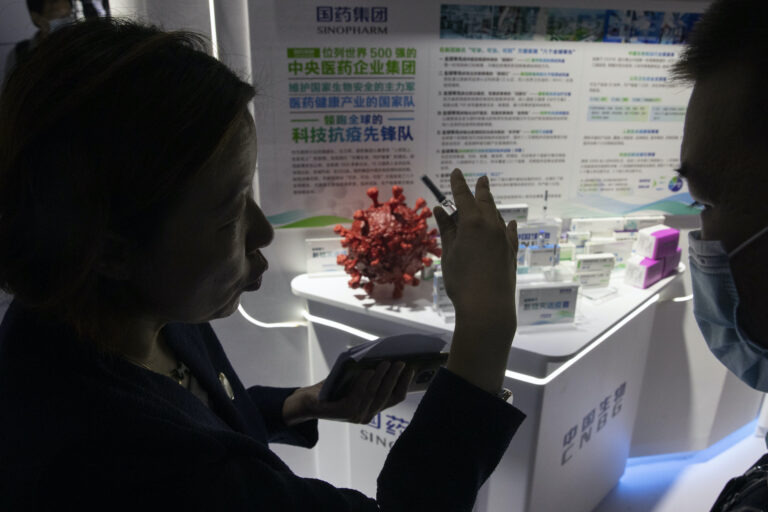 A promoter talks about the COVID-19 vaccine produced by Sinopharm subsidiary CNBG during a trade fair in Beijing on Sunday, Sept. 6, 2020. (AP Photo/Ng Han Guan)
