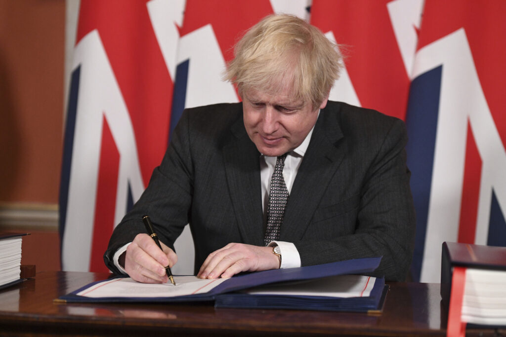 Britain Brexit Britain's Prime Minister Boris Johnson signs the EU-UK Trade and Cooperation Agreement at 10 Downing Street, London Wednesday Dec. 30, 2020. (Leon Neal/Pool via AP)