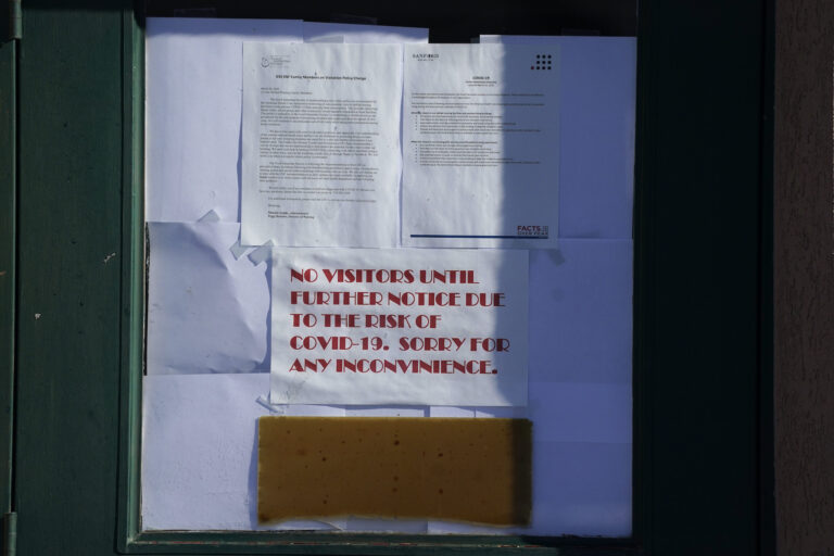 Signs hang on the door to the Good Samaritan Society care center, which is closed to the public Wednesday, Dec. 30, 2020, in Simla, Colo. (AP Photo/David Zalubowski)