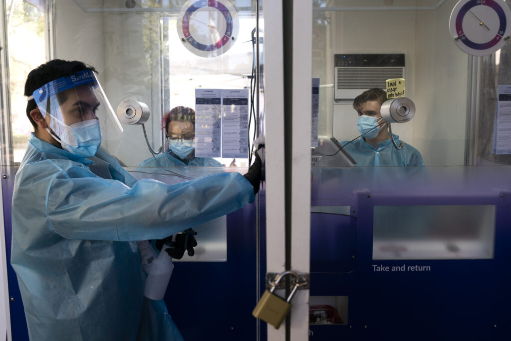 Virus Outbreak US Surge In this Dec. 9, 2020, file photo, test specialist Elijah Sanchez disinfects a testing booth at a COVID-19 testing site in Los Angeles.