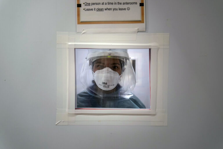 Registered nurse Nicole Grecco looks through a small window while working in a COVID-19 unit at Mission Hospital