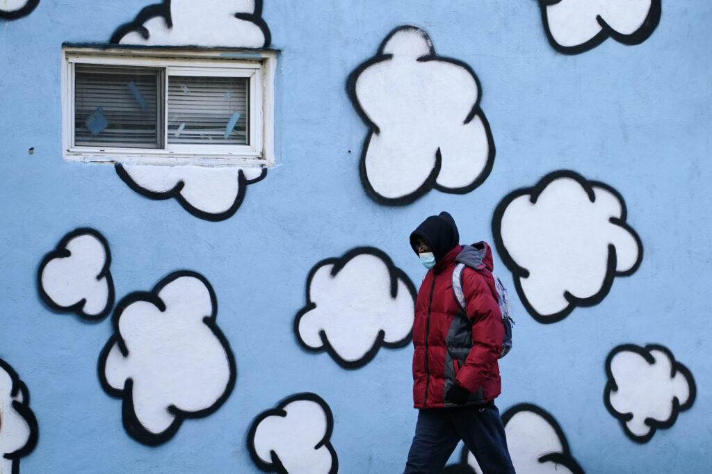 A person wearing a face mask to protect against the spread of the coronavirus walks along Market Street