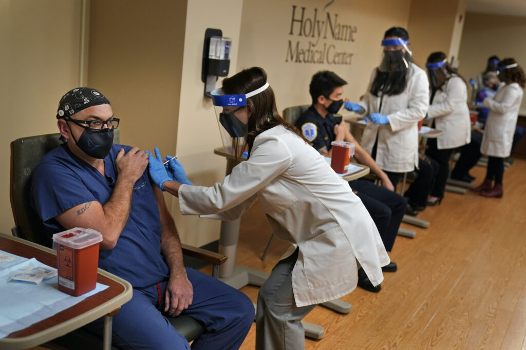 Virus Outbreak New Jersey Nurse Reynaldo Pella, left, was one of five staff members to simultaneously receive the first doses of the COVID-19 vaccine