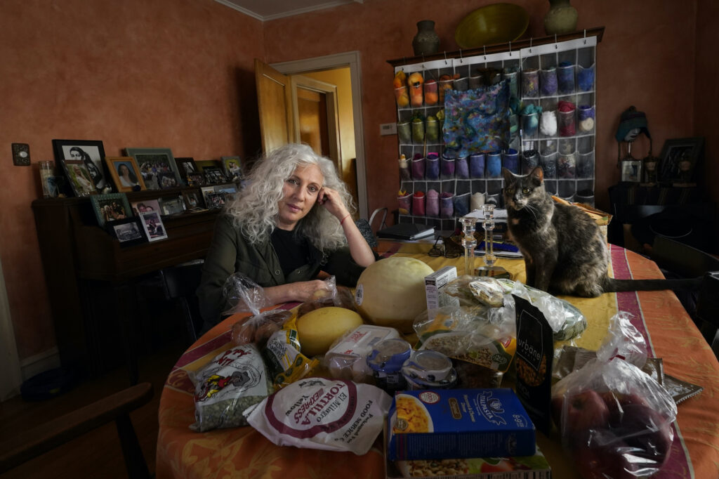APTOPIX Hunger In America Phyllis Marder poses with her cat, Nellie, with food she recently obtained from a local food bank in the dining room of her home