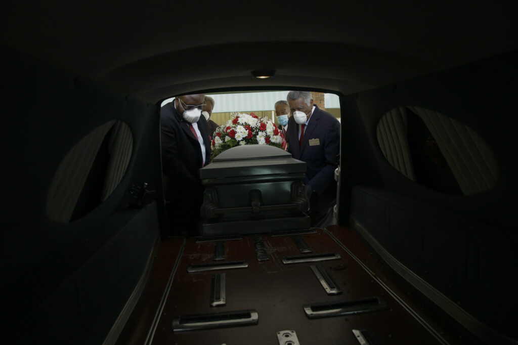 Cordarial O. Holloway, Robert L. Albritten, Eddie Keith, Ronald Costello Mortician Cordarial O. Holloway, foreground left, funeral director Robert L. Albritten, foreground right, and funeral attendants Eddie Keith, background left, and Ronald Costello place a casket into a hearse