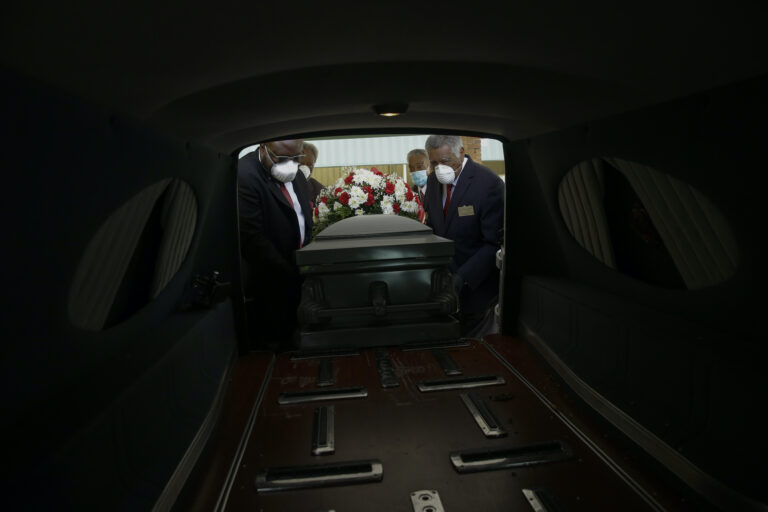 Mortician Cordarial O. Holloway, foreground left, funeral director Robert L. Albritten, foreground right, and funeral attendants Eddie Keith, background left, and Ronald Costello place a casket into a hearse