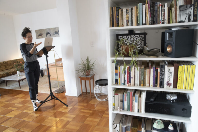 Netta Yerushalmy speaks to the other participants on her computer during a Zoom meeting dance rehearsal in her living room