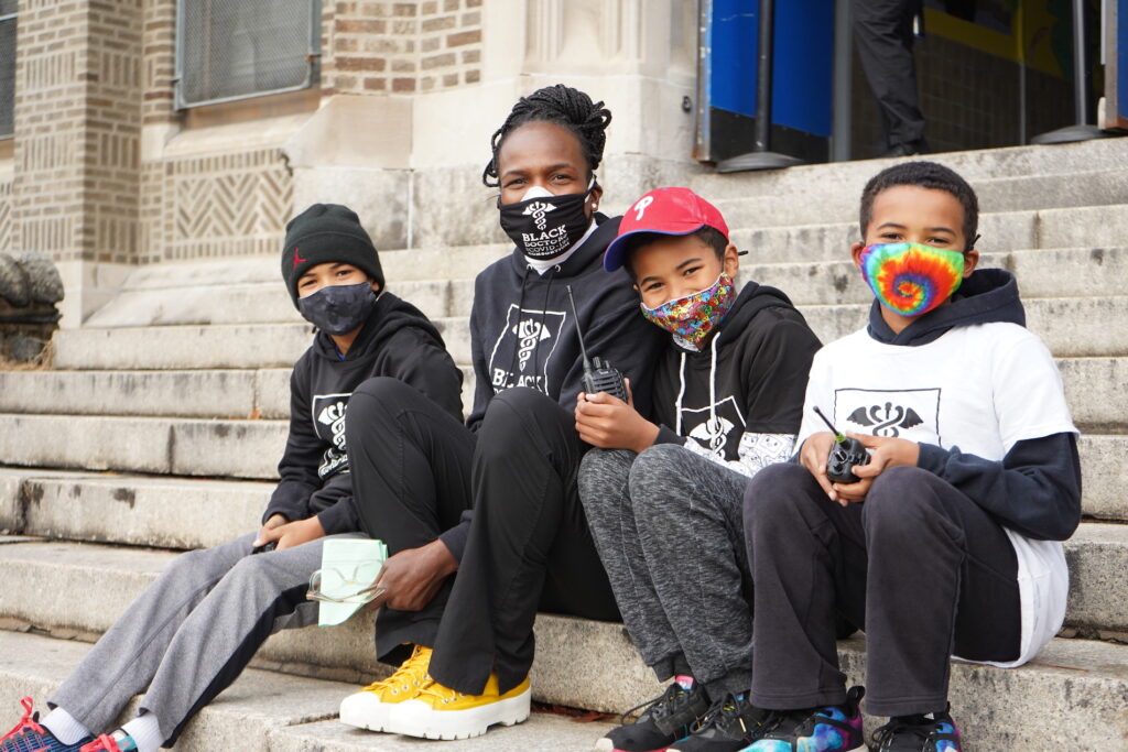 DSC05779 Dr. Ala Stanford, founder of the Black Doctors COVID-19 Consortium, sits outside of the testing event with her three sons who volunteered to help. (Kenny Cooper/WHYY)