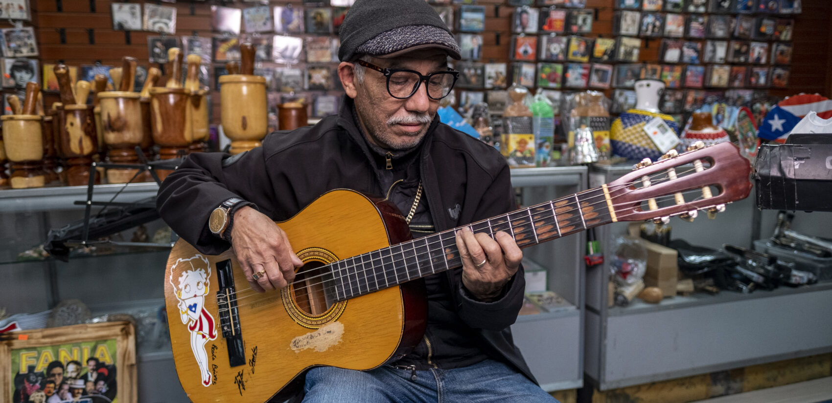 Friend and regular, Johnny Cruz playing the guitar at Centro Musical. His guitar features Betty Boop wearing the Puerto Rican flag. | Amigo y habitual, Johnny Cruz tocando la guitarra en Centro Músical. Su guitarra presenta a Betty Boop con la bandera de Puerto Rico.