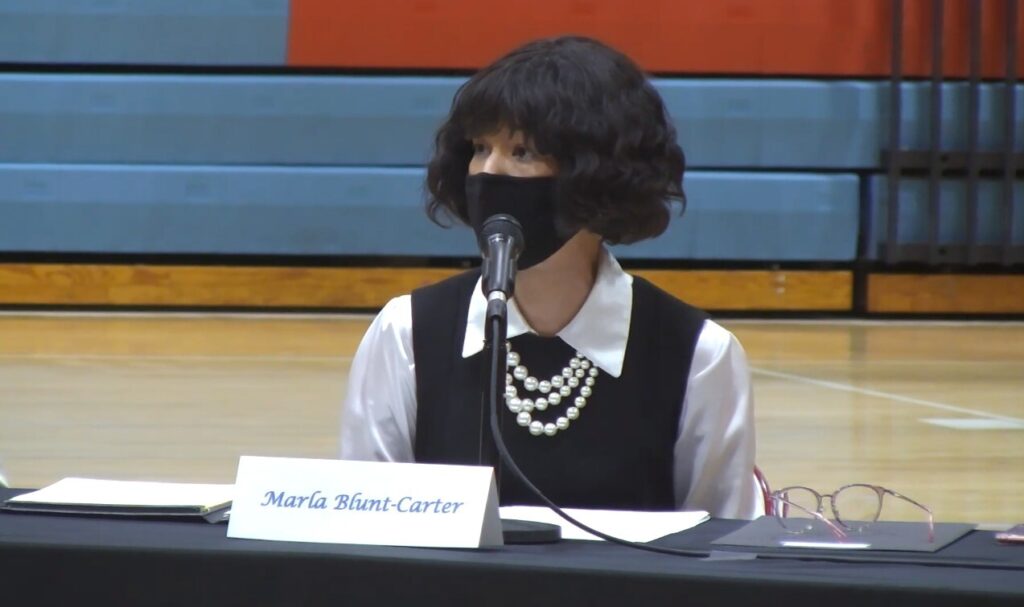 Marla Elector Marla Blunt-Carter sits in front of a mic while wearing a mask