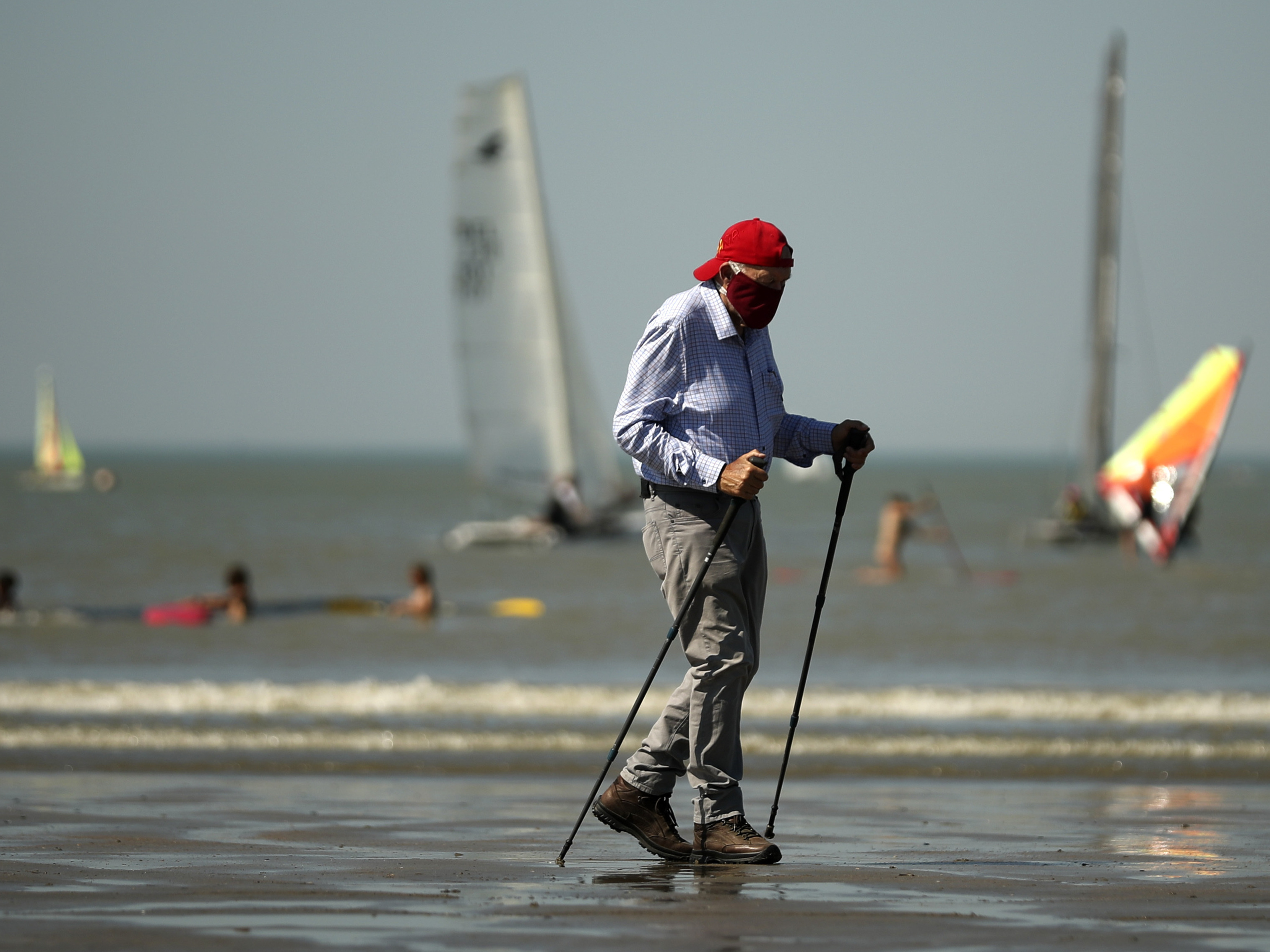 A man, wearing a face mask to fight against the spread of the coronavirus, walks along Zoute beach