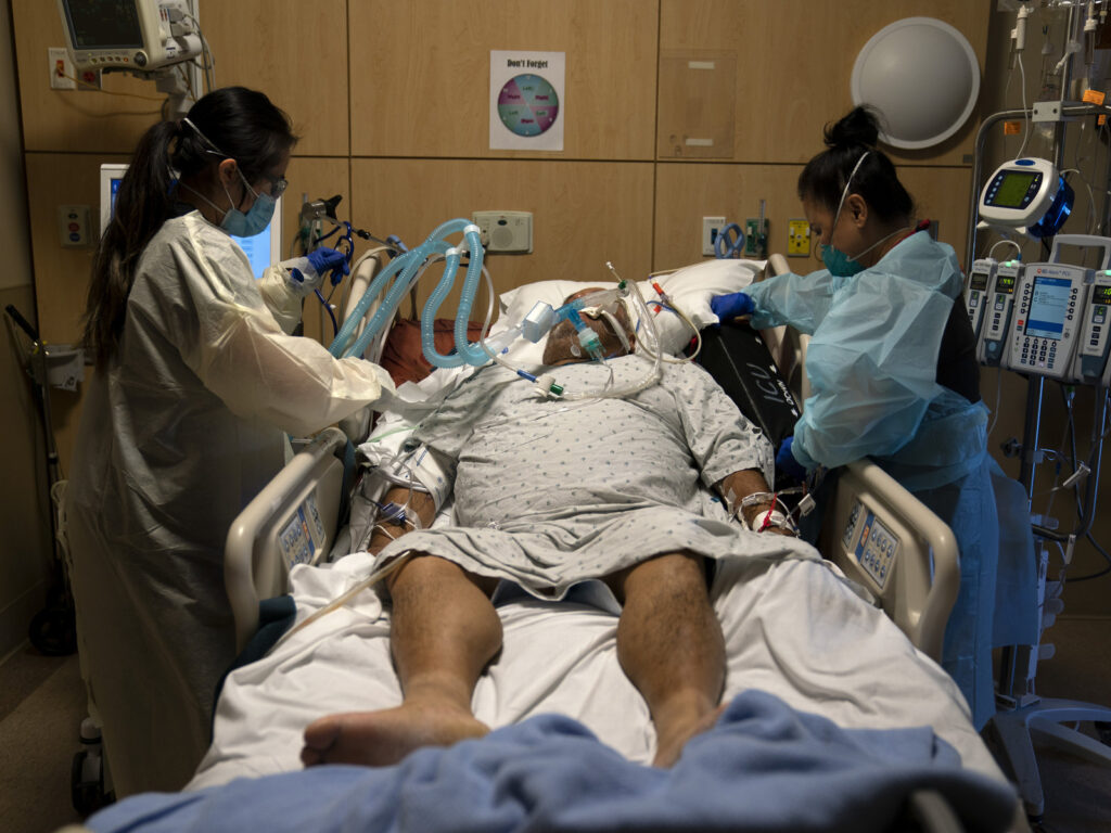 Registered nurses Karen Ross, right, and Angela Nguyen assist a COVID-19 patient at Providence Holy Cross Medical Center