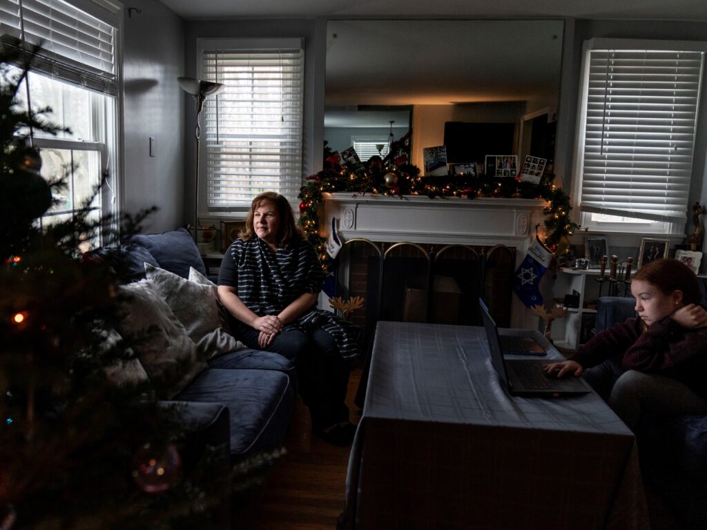 Eileen Carroll, left, sits for a portrait as her daughter, Lily, 11, attends school remotely from their home in Warwick, R.I. on Dec. 16. When Carroll’s other daughter tested positive for the coronavirus, state health officials told her to notify anyone her daughter might have been around. Contact tracers, she was told, were simply too overwhelmed to do it. Eileen Carroll, left, sits for a portrait as her daughter, Lily, 11, attends school remotely from their home in Warwick, R.I