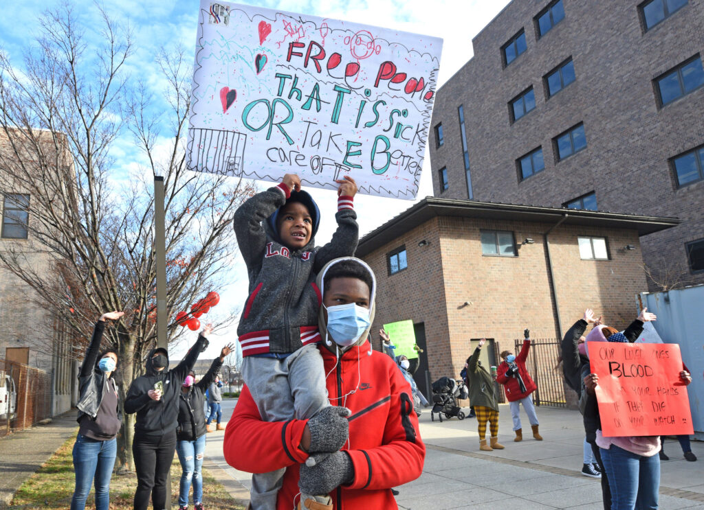 camden_jails_coronavirus_AS_120720_07 Leemaj Banks, 5, holds a sign while in the arms of his uncle Geovanni Andujar