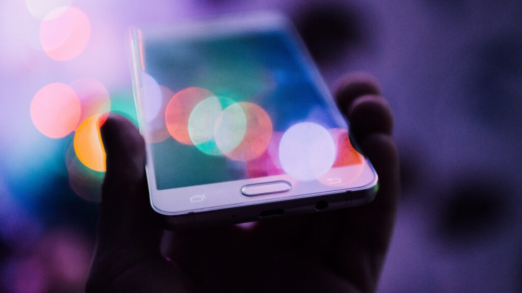 cell_phone_generic_rodion_kutsaev_unsplash A person holds up a white cell phone.
