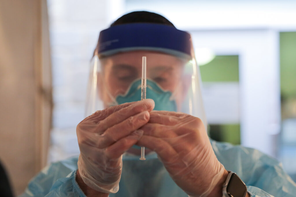 coronavirus_vaccine_NJ_govs_office_122820.jpg A health care worker holds up a syringe containing a COVID-19 vaccine at Roosevelt Care Center