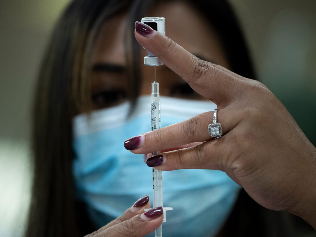 The U.S. is unlikely to meet its goal of vaccinating 20 million Americans by the end of the year, health officials said this week. A pharmacist dilutes the Pfizer COVID-19 vaccine while preparing it to administer to staff and residents at the Goodwin House Bailey's Crossroads, a senior living community in Falls Church, Virginia, on December 30, 2020.