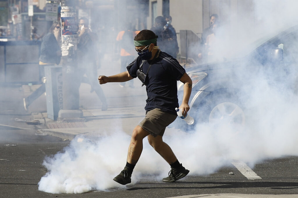 A protester kicks a tear gas canister fired by police as protests continue Sunday, May 31, 2020, in Philadelphia. (AP Photo/Matt Rourke)