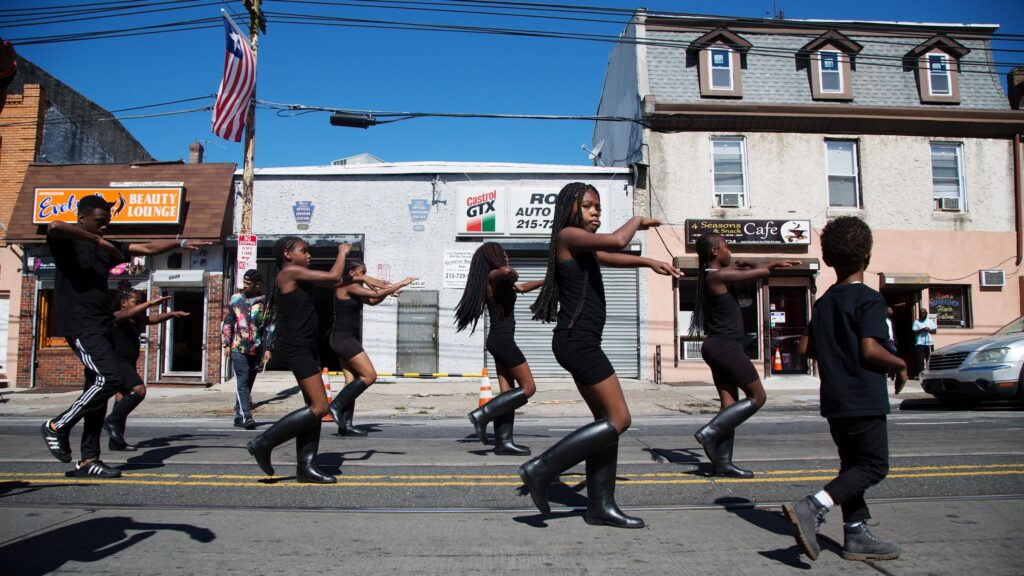 006-2 The Mass Konfusion drill team makes their way down Woodland Avenue as a Liberian flag hangs above the street at Southwest Pride Day in 2017. (Annie Risemberg for WHYY)