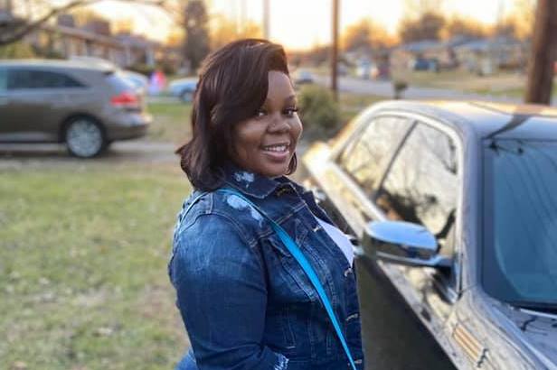 Breonna Taylor stands in front of a car