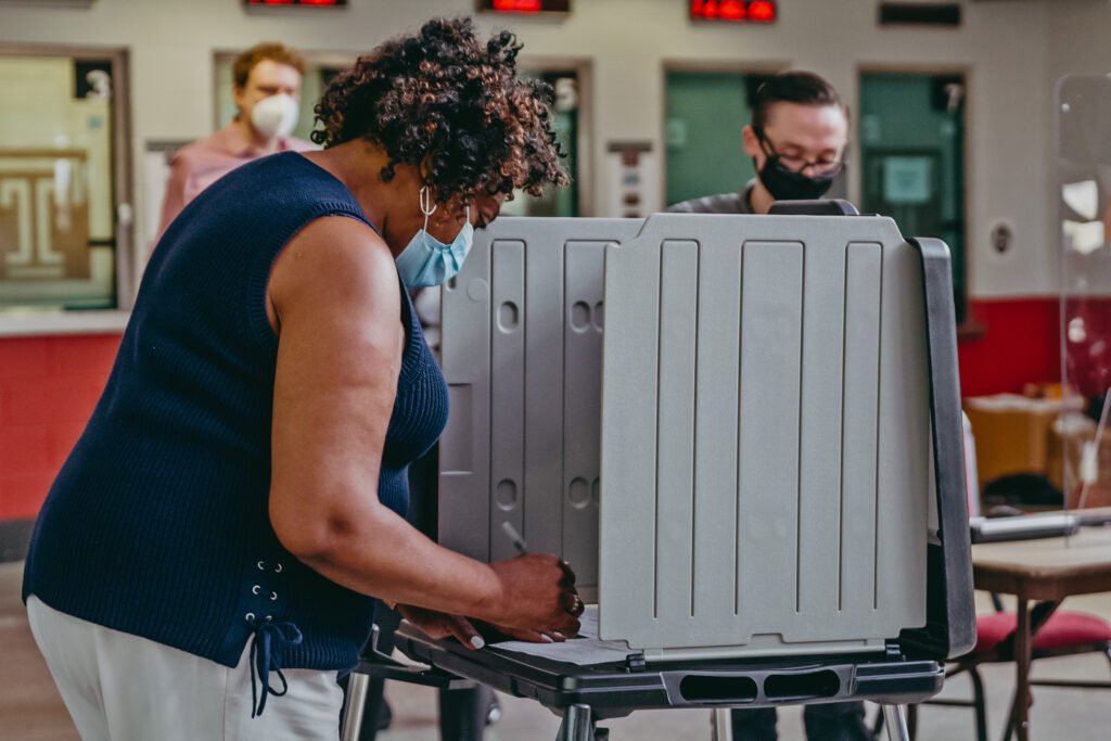 The first voter at the Liacouras Center satellite election office, Priscilla Bennet, fills out her official mail-in ballot, and demonstrates for the press the process. (Kimberly Paynter/WHYY)