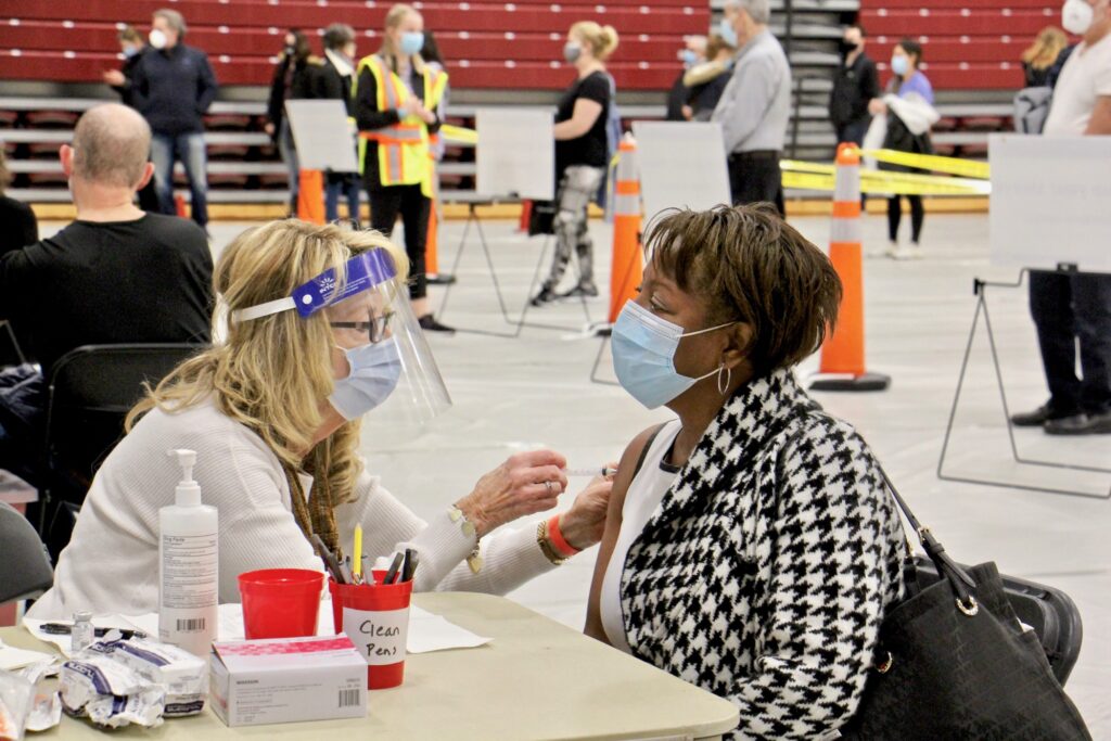 2021 01 06-e lee-pat dehorsey cornelia lavong-blue bell pa montgomery county community college-covid vaccination clinic Registered nurse Pat DeHorsey vaccinates Cornelia Lavong at a county run clinic