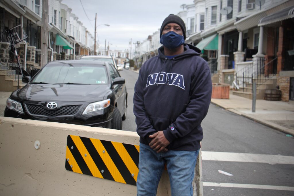 2021 01 27-e lee-derrick smith-philadelphia north simpson street 2 Derrick Smith, wearing a face mask, stands on Simpson Street in front of a traffic barrier