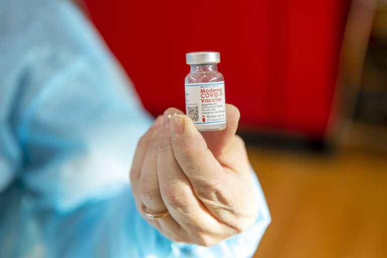 A woman holds a vial of the Moderna COVID-19 vaccine