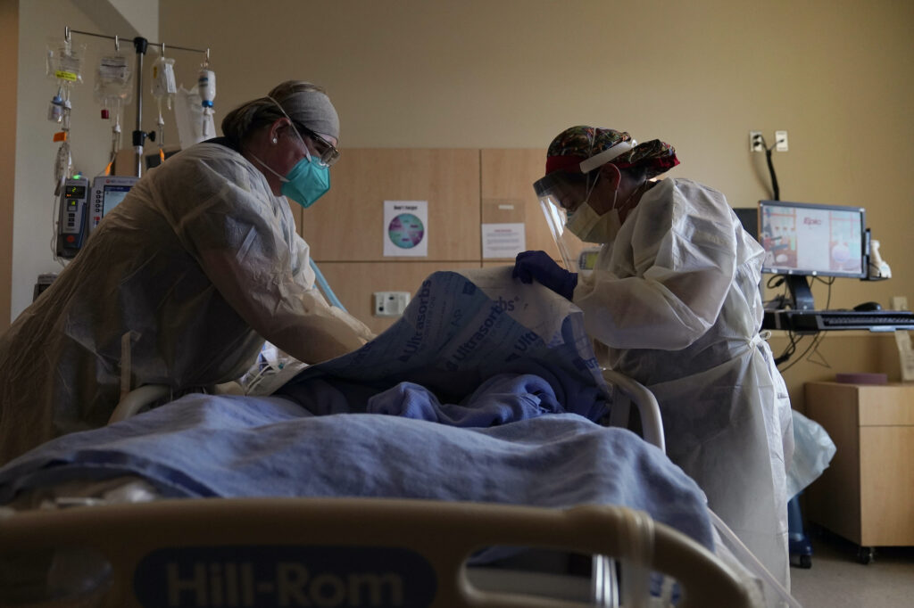 Registered nurses Robin Gooding, left, and Johanna Ortiz treat a COVID-19 patient