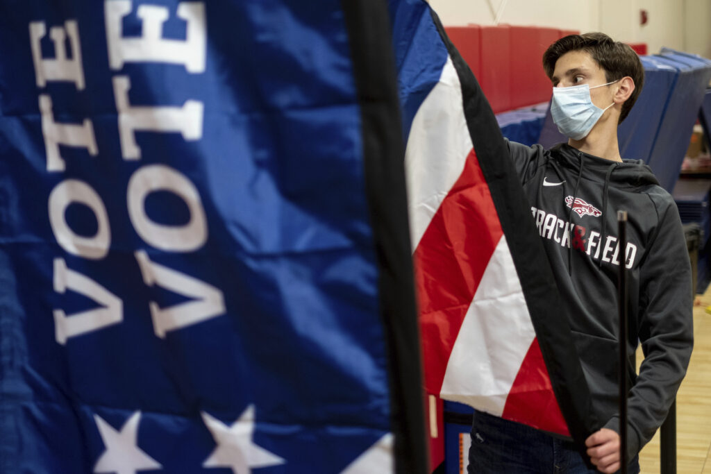 Thomas Hedrich sets up voting flags at a polling location.