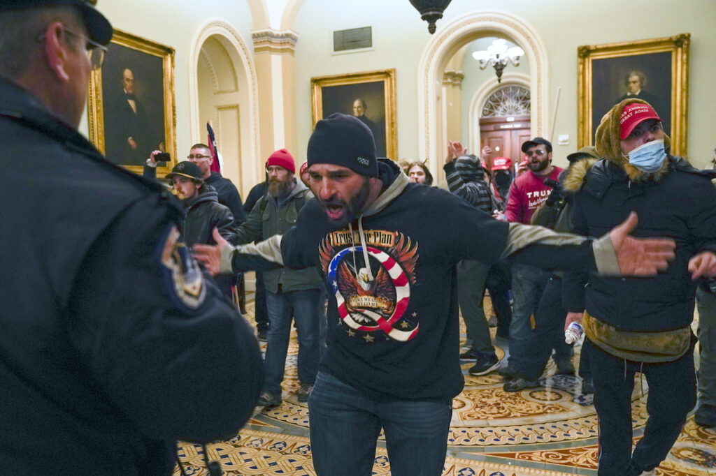 Electoral College Photo Gallery Pro-Trump insurrectionists gesture to U.S. Capitol Police in the hallway outside of the Senate chamber at the Capitol