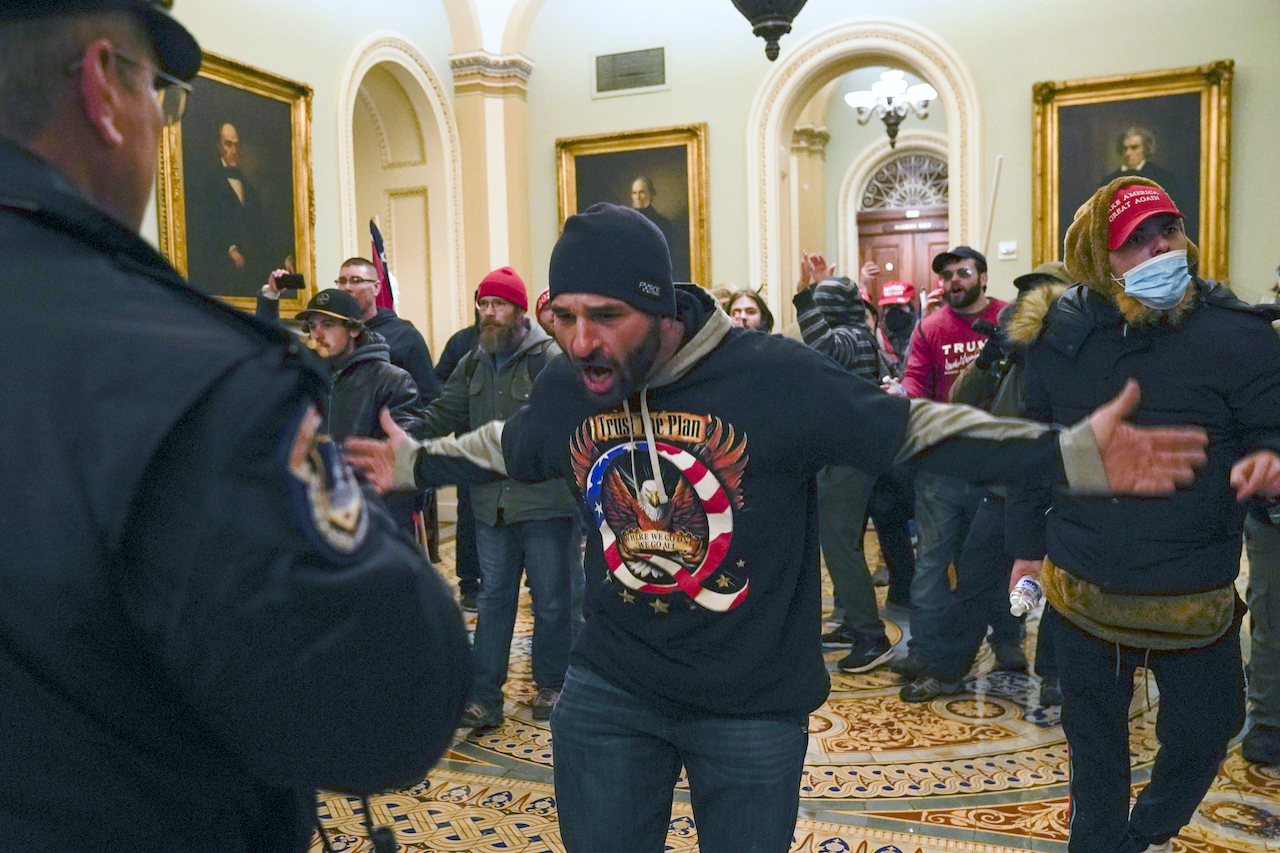 Pro-Trump insurrectionists gesture to U.S. Capitol Police in the hallway outside of the Senate chamber at the Capitol