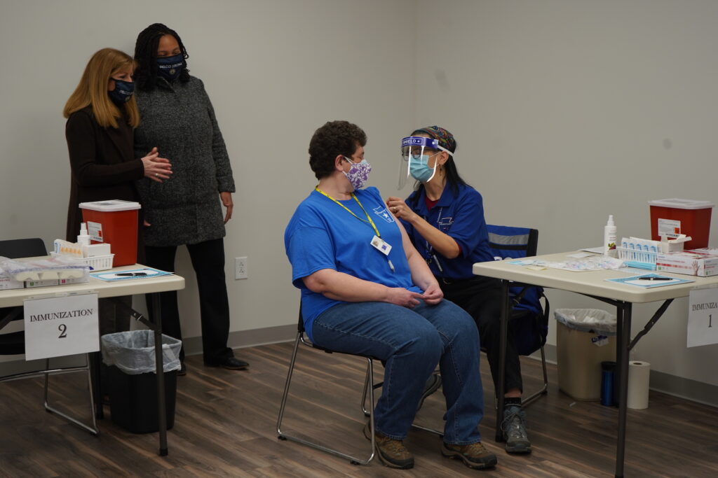 DSC06023 Amy Zoll, a volunteer with the Citizen Corps of Delaware County, becomes the first person to be vaccinated at the ribbon cutting for the new Delaware County Wellness Center. (Kenny Cooper/WHYY)