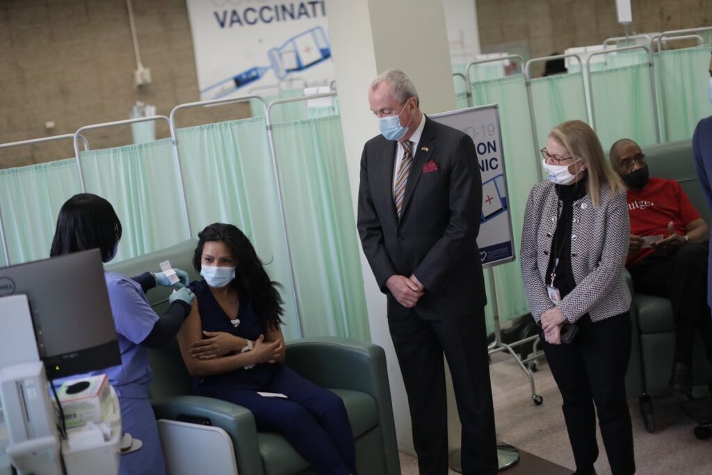 Eq6BAYZXUAEVc96 Gov. Murphy looks on as frontline health care workers at University Hospital in Newark received their second doses of the Pfizer-BioNTech vaccine.