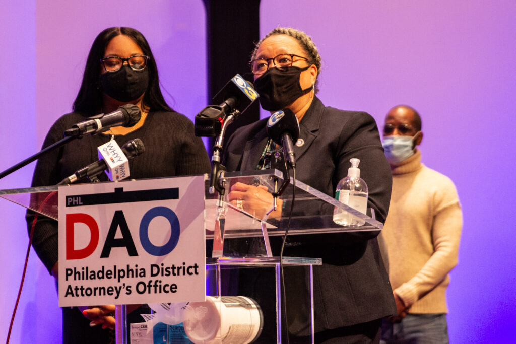 IMG_2519 Myra Maxwell speaks at a podium with a sign stating the Philadelphia District Attorney's Office in front of her.