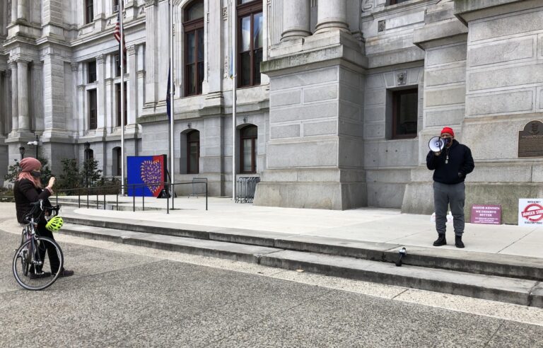 A passerby photographs activist Jamal Johnson who began his hunger strike Monday. (Layla Jones/WHYY)