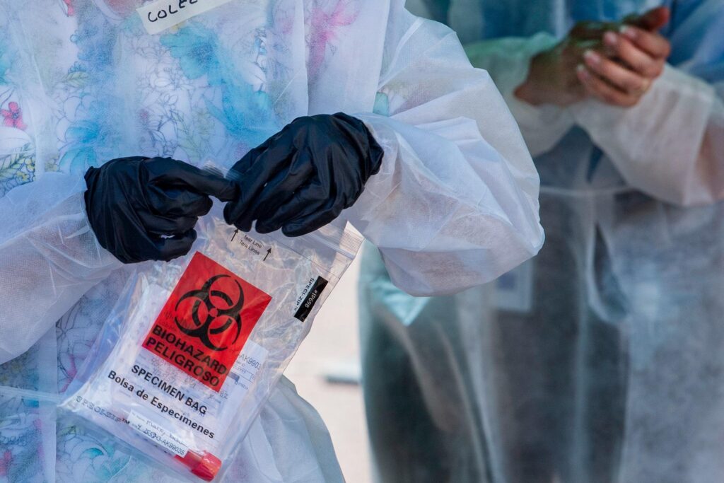 PA_coronavirus_testing_inky_010621 A health care worker holds a sample from a coronavirus test in a sealed plastic bag.