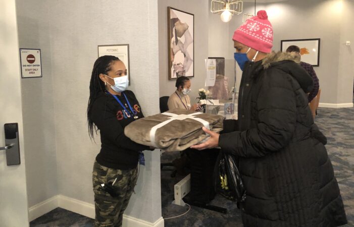 Cassie Brown hands a guest a new blanket. (Cris Barrish/WHYY)