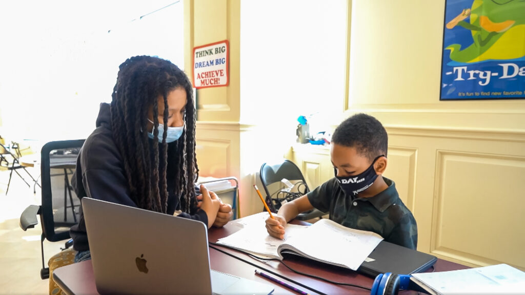 YOK_S3E1 A young black girl and boy studying and doing homework with masks on