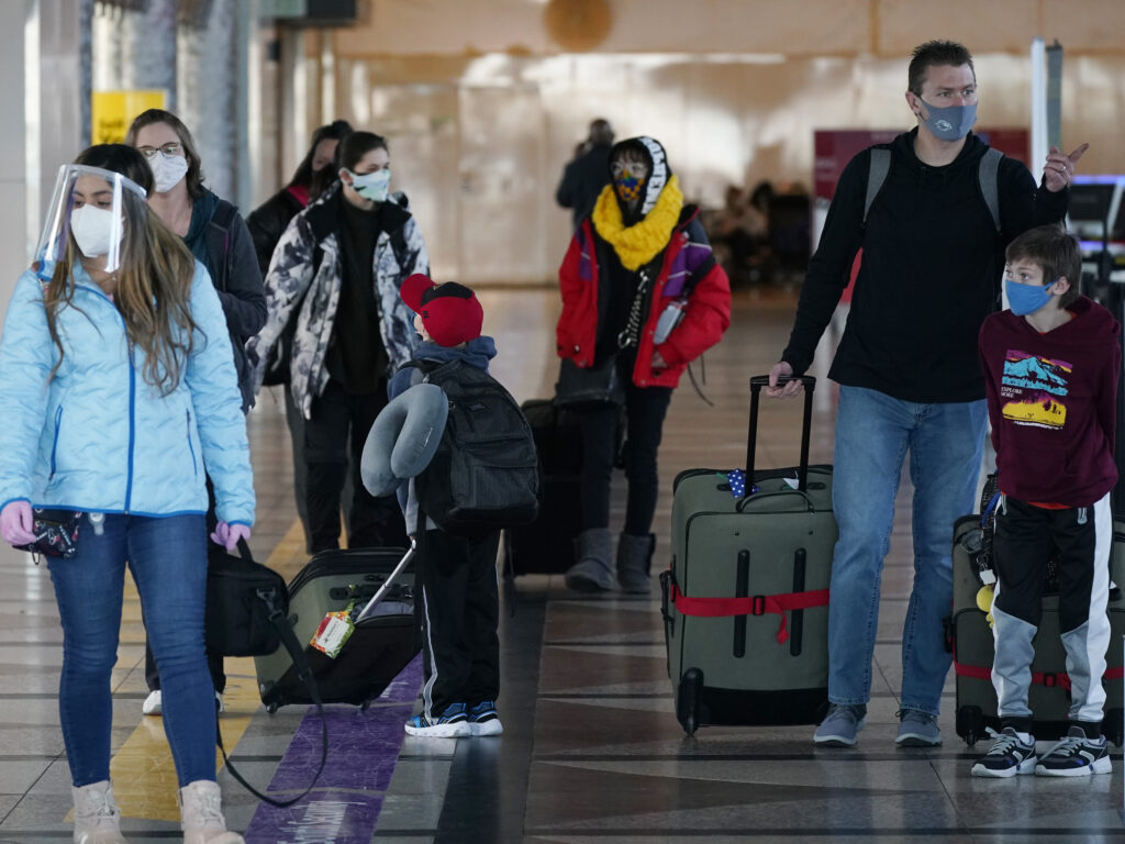 Masked travelers head through the main terminal of Denver International Airport on Dec. 31. Starting Feb. 1, travelers will be required to wear face masks on nearly all forms of public transportation. Travelers wear face masks in the main terminal of Denver International Airport