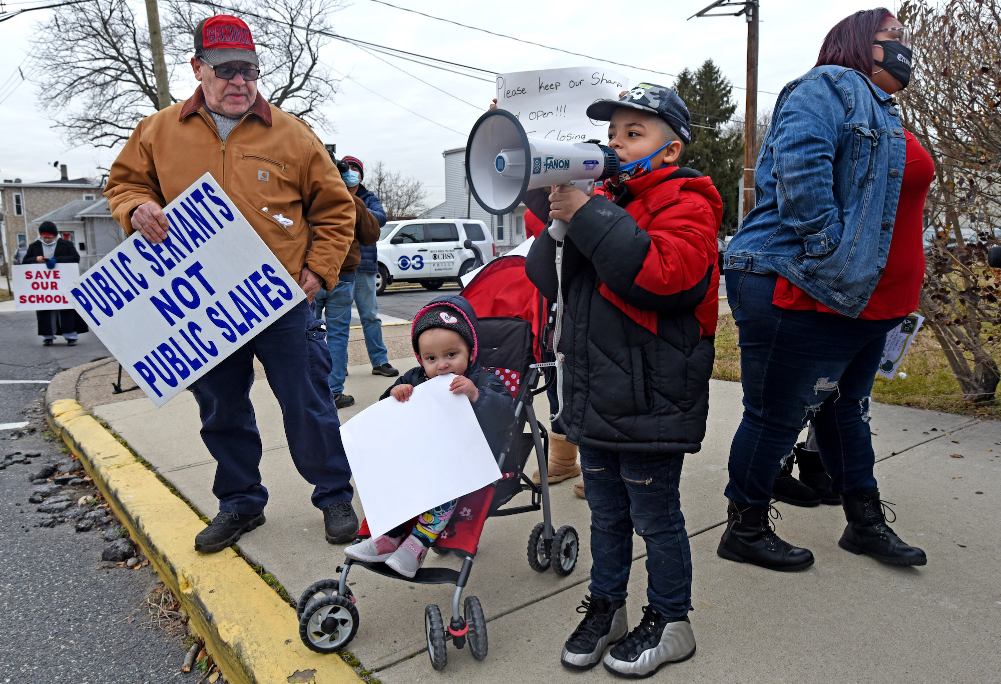 Activist Eulisis Delgado, left, protests school closures with children and their parents in front of Harry C. Sharp Elementary School