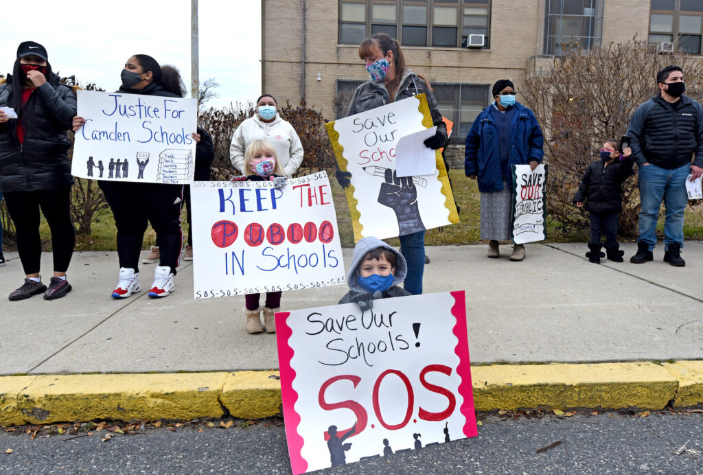 Parents and children hold up signs to 