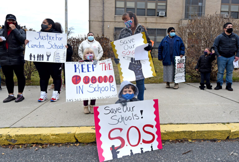 Parents and children hold up signs to 