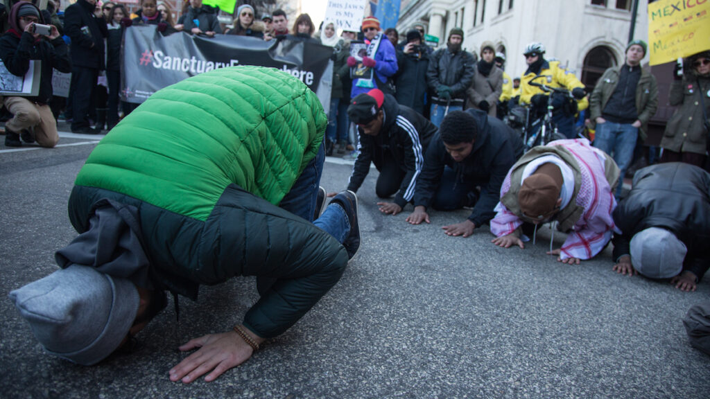 cohen-march_for_humanity-21-1 Abdulazeem Sheikh, 22, leads others from the group Young Muslims in afternoon prayer. Thousands of protesters gathered at Thomas Paine Plaza for a March for Humanity in support of refugees and immigrants in Philadelphia on Feb. 4, 2017. (Emily Cohen for WHYY)
