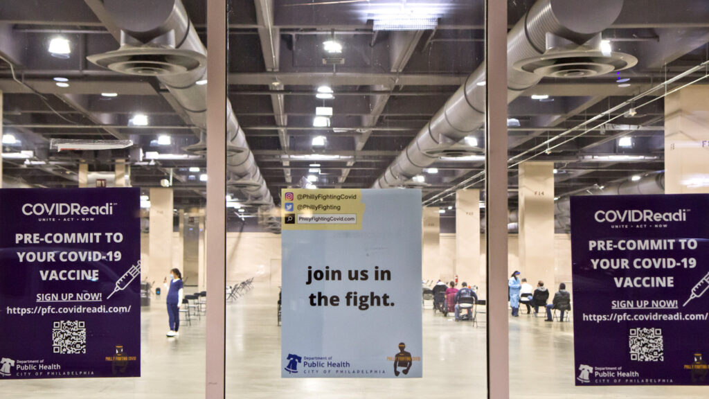 conventioncenter-vaccineclinic-phillyfightingcovid-02crop Signs on the window of the city's first mass vaccination at the Pa. Convention Center on its opening day, Jan. 8. (Kimberly Paynter/WHYY)