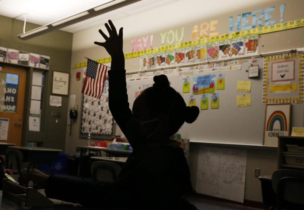 A first grade student raises her hand at Mary L. Fonseca Elementary School in Fall River, Mass., in November. A first grade student raises her hand