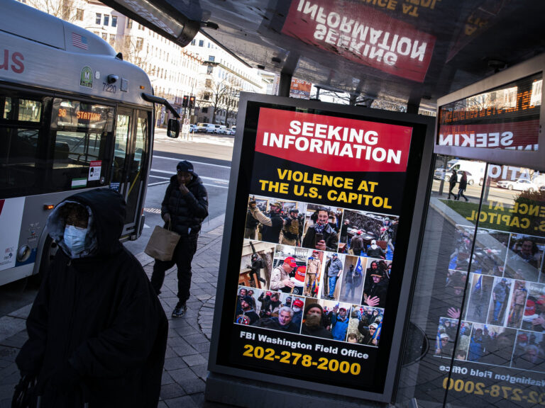 At a bus stop on Pennsylvania Avenue Northwest in Washington, D.C., a notice from the FBI seeks information about people pictured during the riot at the U.S. Capitol