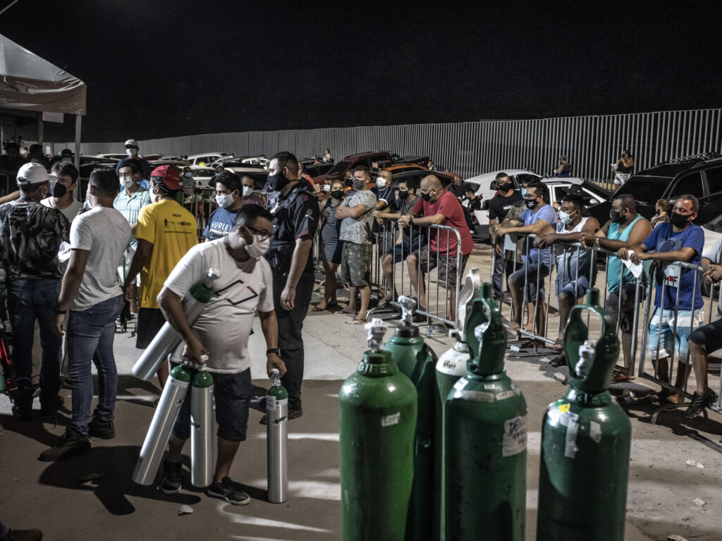 Workers check oxygen tanks at a hospital in Manaus, Brazil. Severe oxygen shortages as a second coronavirus wave is surging have prompted local authorities to airlift patients to other parts of Brazil. People wearing protective masks wait in line to refill oxygen tanks in Manaus