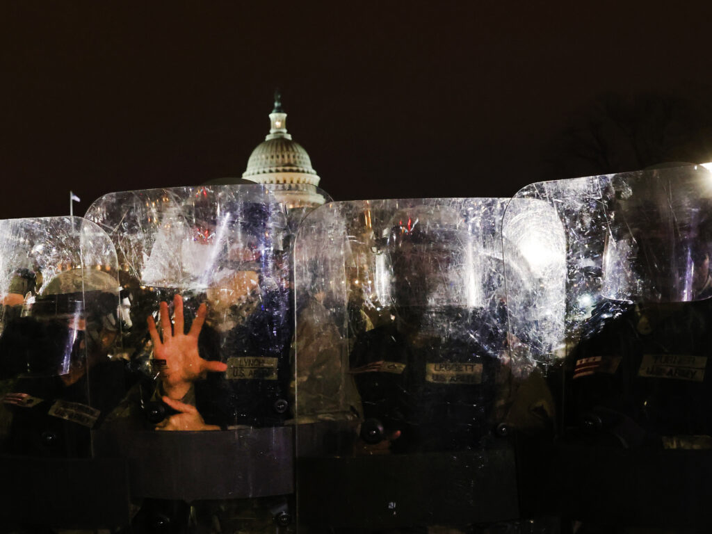 Police officers with face shields stand outside the Capitol